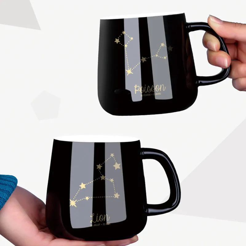 Black mugs with star constellation designs held by hands on a white background