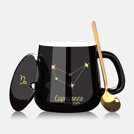 Black mug with Capricorn zodiac design, gold spoon, and lid on a white background