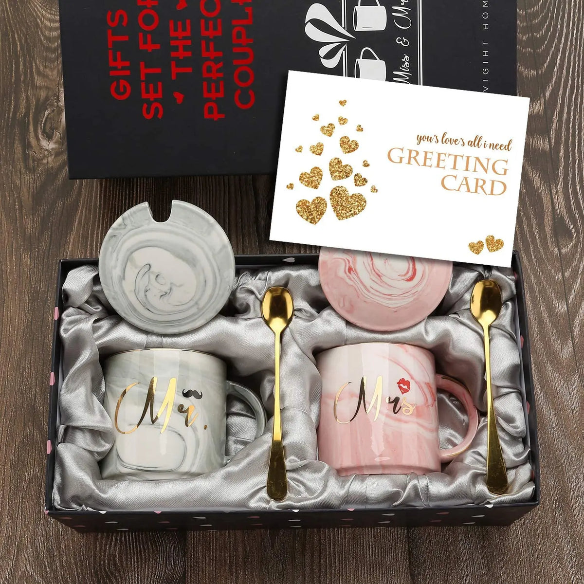 Gift set with two mugs, spoons, and a card in a box on a wooden surface.