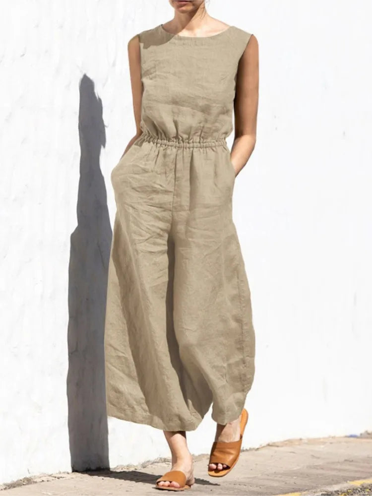 Person wearing a beige jumpsuit against a white wall