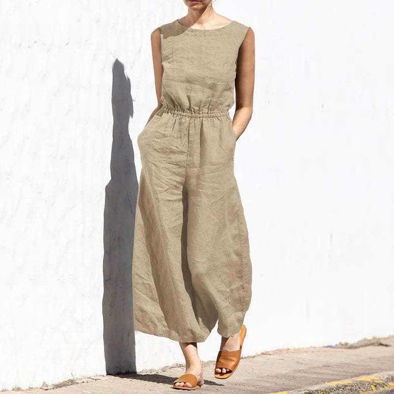 Person wearing a beige jumpsuit against a white wall