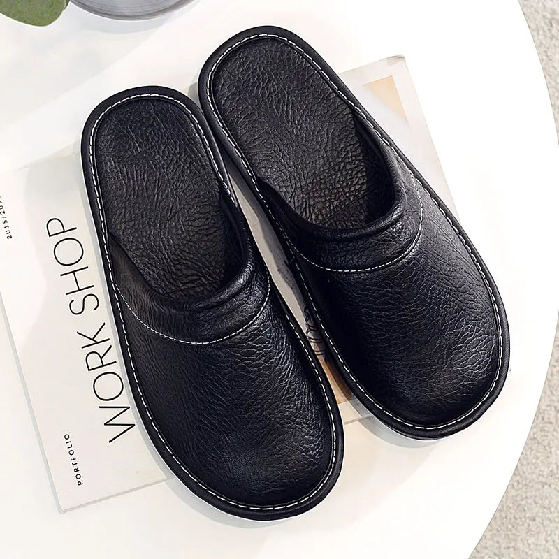 Pair of black slippers on a white surface with a magazine underneath.