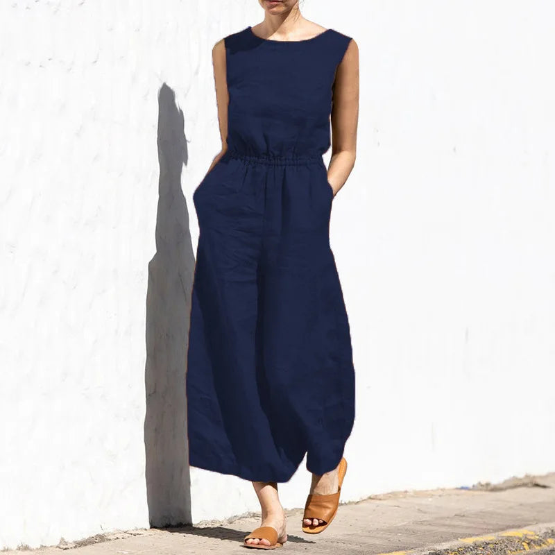 Person wearing a navy blue sleeveless dress against a white wall.