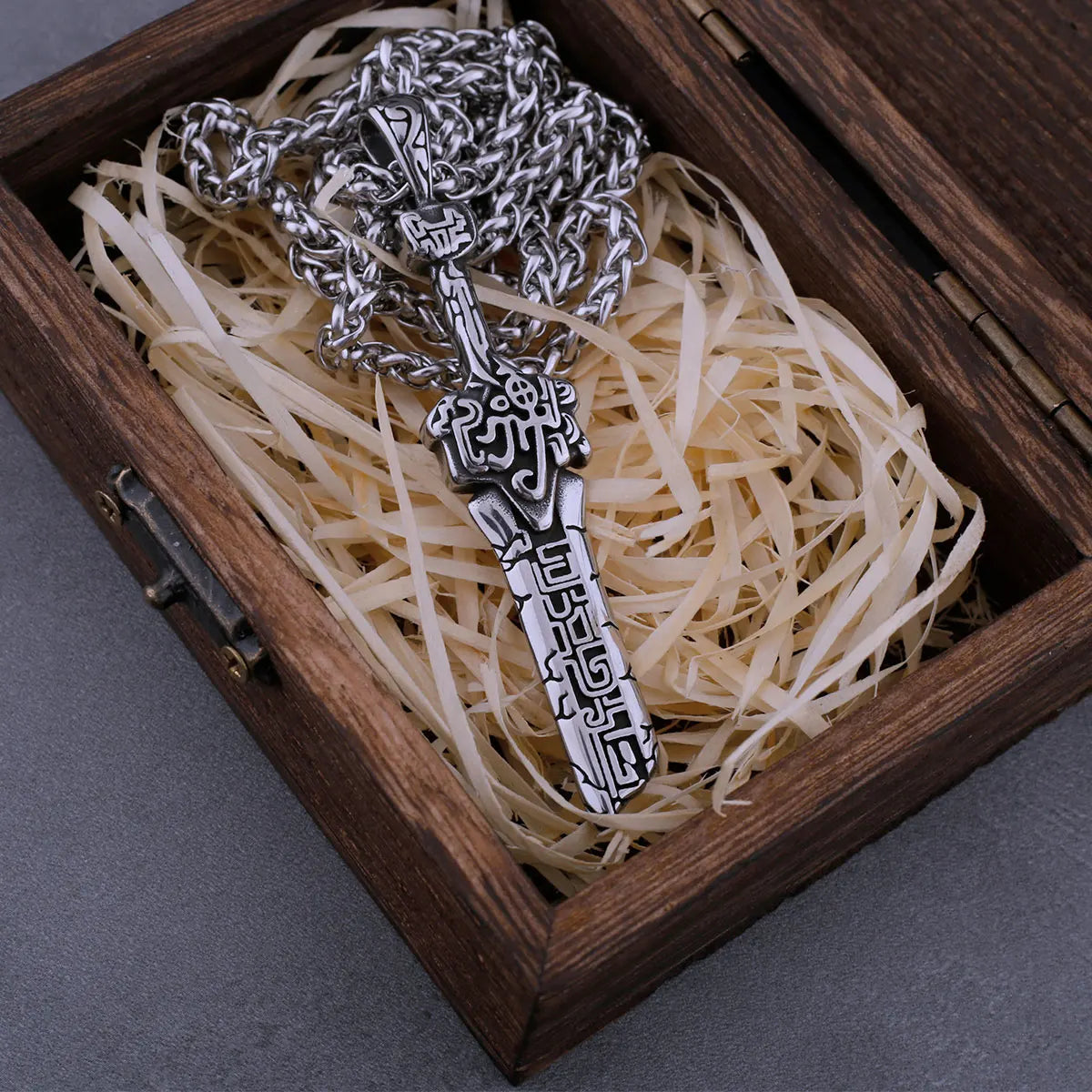 Silver key-shaped pendant in a wooden box with shredded paper