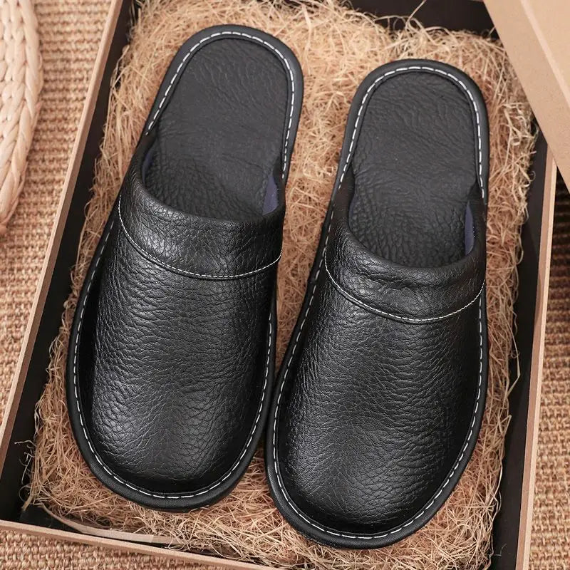 Pair of black leather slippers on a textured surface