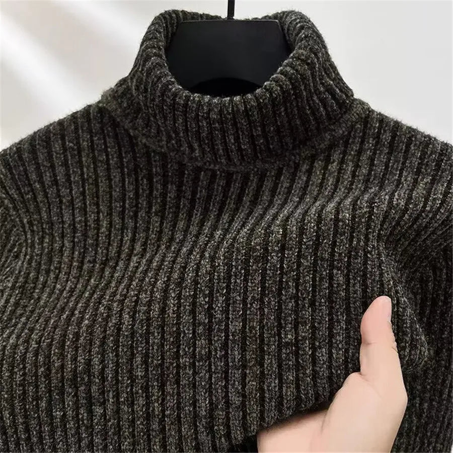 Dark gray ribbed turtleneck sweater held by a hand against a neutral background