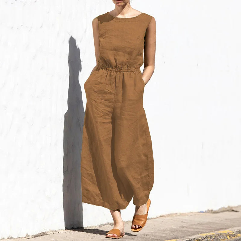 Person wearing a brown sleeveless jumpsuit against a white wall.