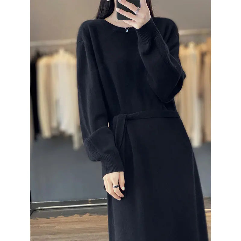 Person wearing a long black dress with a belt in a clothing store.