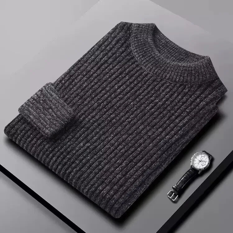 Gray ribbed sweater on a gray surface with a watch beside it