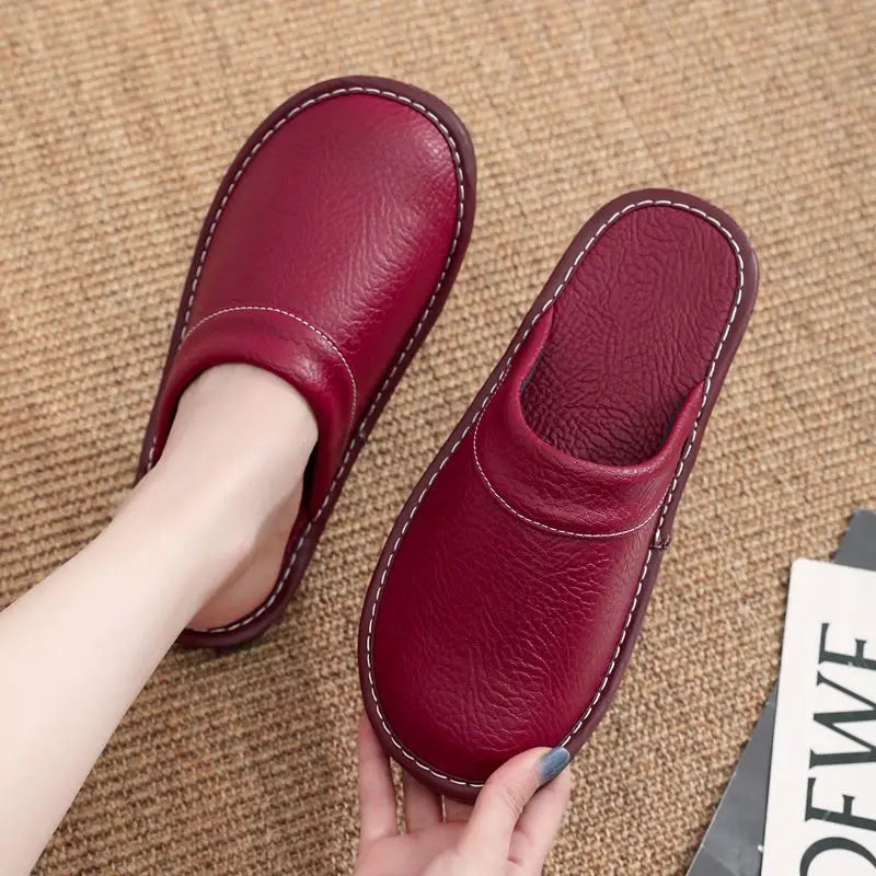 Red slippers being held on a textured brown surface