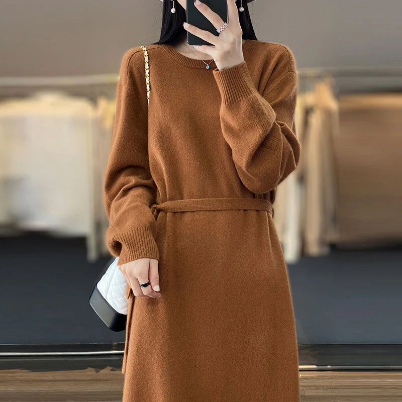 Person wearing a brown dress with a belt, holding a phone, in an indoor setting.