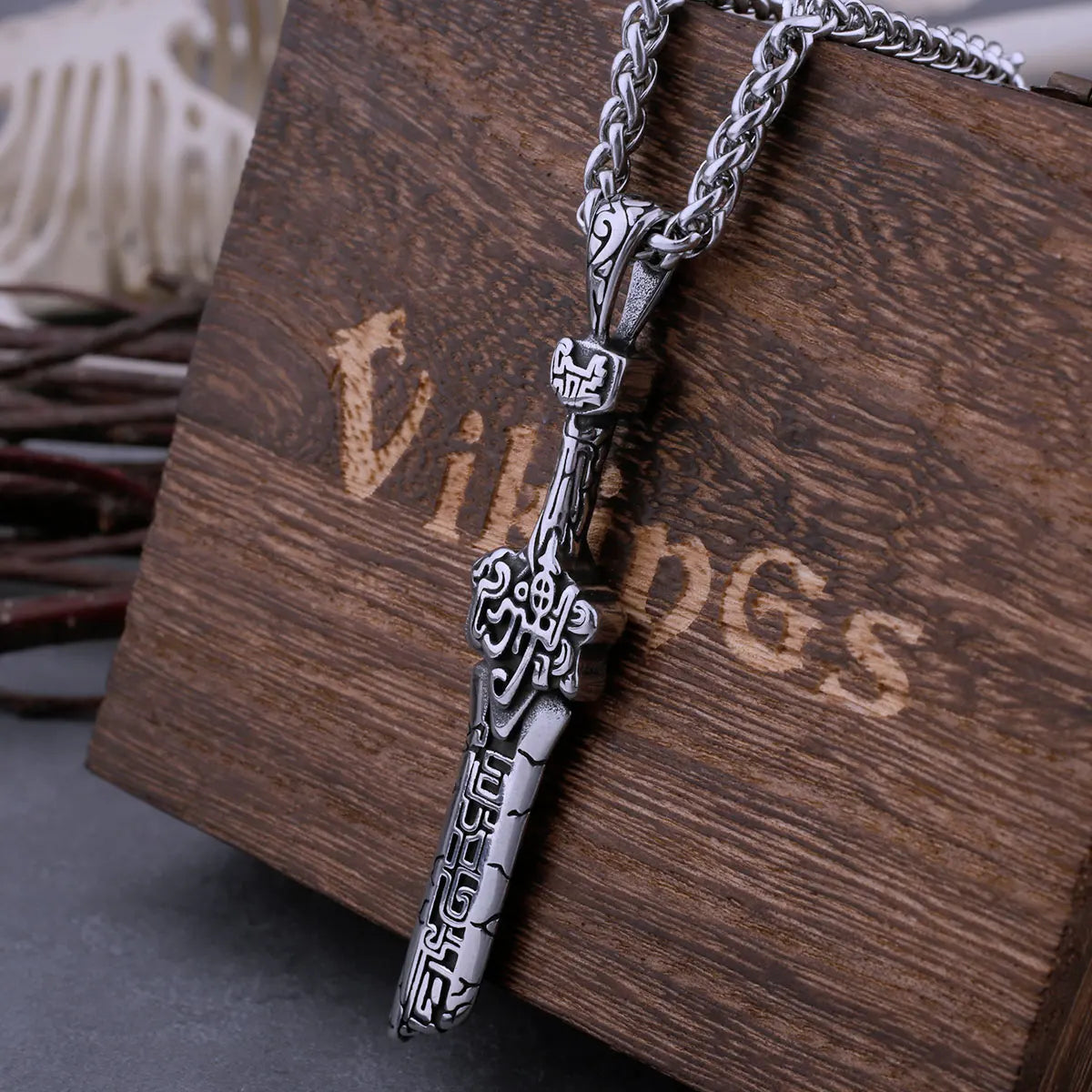 Silver pendant necklace on a wooden surface with 'Vikings' branding.